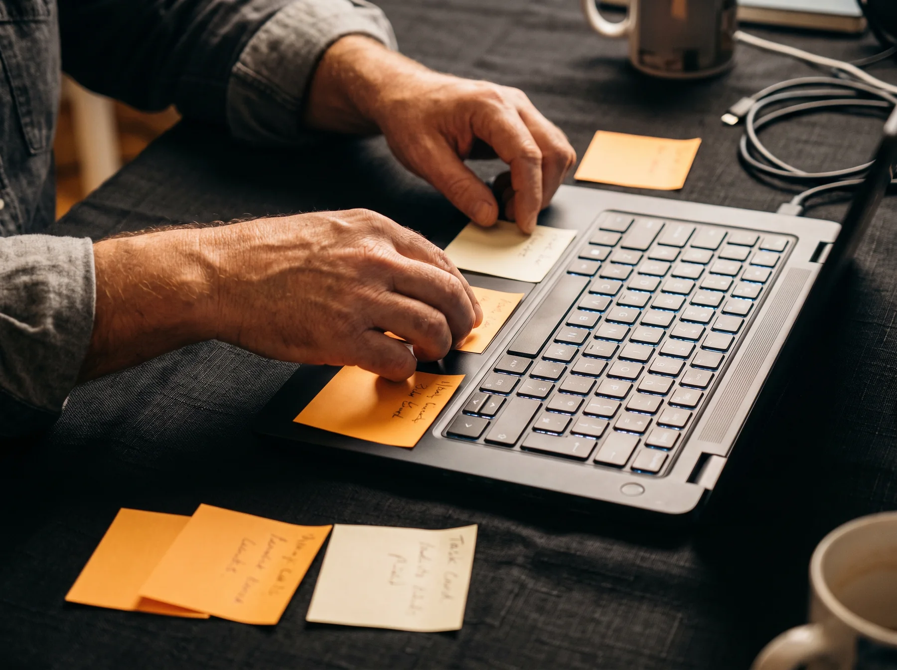 Hands arranging notes beside a laptop keyboard